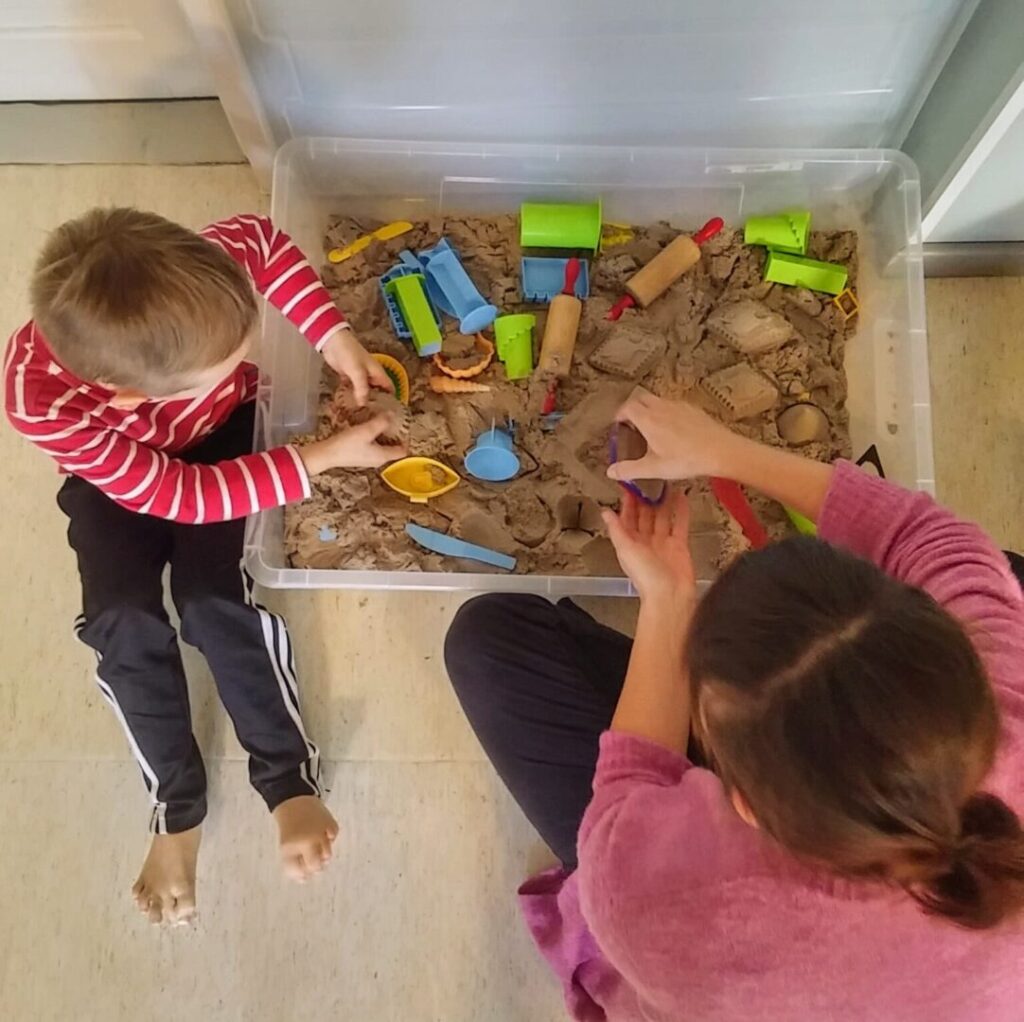 kaksi lasta leikkii sisätiloissa hiekalla