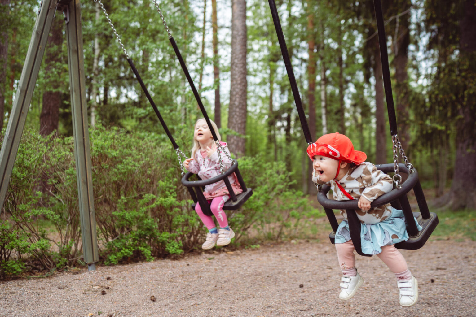 Kaksi pientä lasta keinuu.